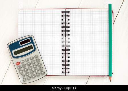 Calculatrice électronique et carnet à spirales sur le fond en bois blanc Banque D'Images