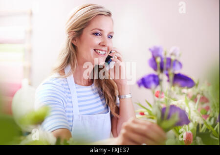 Fleuriste fleurs et sourire organiser talking on cell phone Banque D'Images