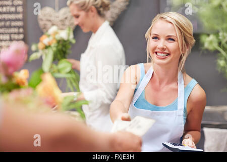 Fleuriste sourire étant payés par le client dans le magasin de fleurs Banque D'Images