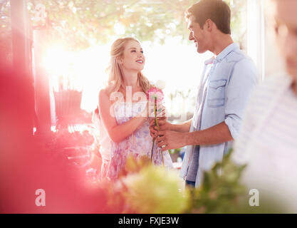 Man giving woman flowers in flower shop Banque D'Images