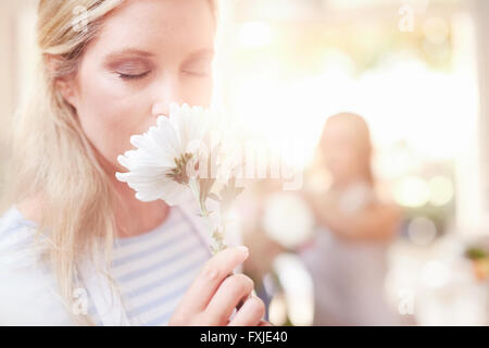 Woman smelling white daisy gerber Banque D'Images