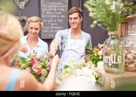 Prendre de l'argent à partir de fleuriste femme in flower shop Banque D'Images