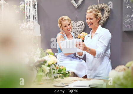 Smiling fleuristes using digital tablet in flower shop Banque D'Images