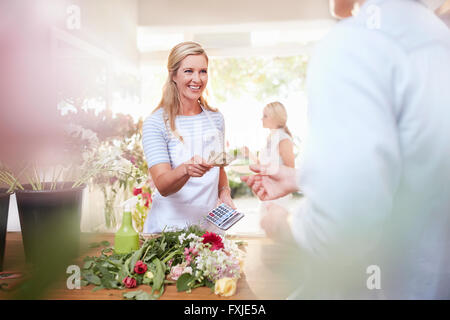 Fleuriste sourire donnant client changer in flower shop Banque D'Images