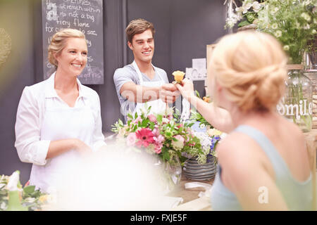 Femme en rose donnant fleuriste magasin de fleurs Banque D'Images