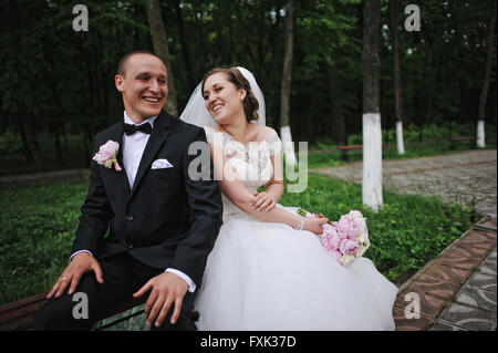 Happy wedding couple assis sur un banc appuyé dos à l'autre Banque D'Images