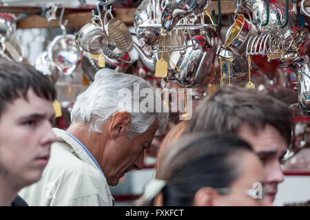 L'homme aux cheveux gris parcourt l'argenterie sur un étal de marché à Portobello Road, Londres, Angleterre, Royaume-Uni. Banque D'Images