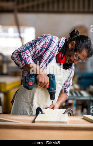 Carpenter de percer un trou dans une planche en bois Banque D'Images