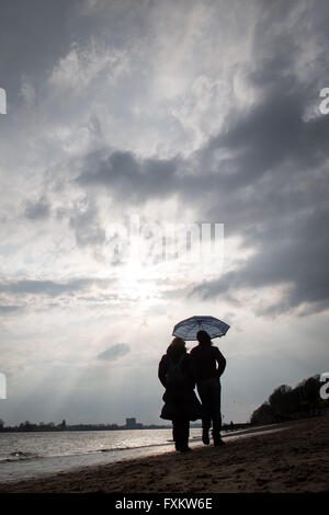 Deux femmes se serrent sous un parapluie comme ils faire une promenade sur les rives de l'Elbe à Hambourg, Allemagne, 16 avril 2016. Photo : Christian Charisius/dpa Banque D'Images