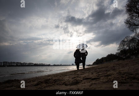Deux femmes se serrent sous un parapluie comme ils faire une promenade sur les rives de l'Elbe à Hambourg, Allemagne, 16 avril 2016. Photo : Christian Charisius/dpa Banque D'Images