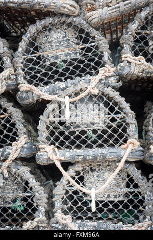 Des casiers à crabe et homard ou la pêche à la nasse empilées sur un quai du port Banque D'Images