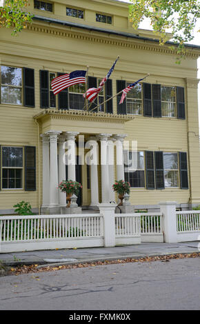 Extérieur d'une maison de style fédéral jaune de Stonington Connecticut. La maison a trois volets, noir et un drapeau américain whi Banque D'Images