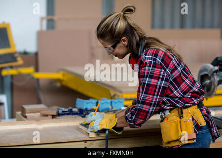 Female carpenter marquage sur planche en bois avec un crayon Banque D'Images