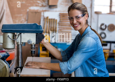 Female carpenter de percer un trou dans une planche en bois Banque D'Images