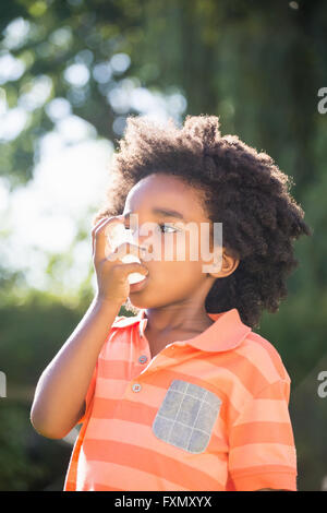 Joli garçon de race mixte à l'aide d'un spray d'asthme Banque D'Images