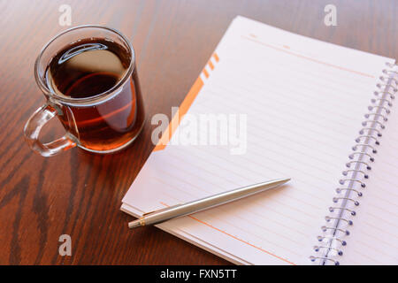 Ouvrir un ordinateur portable blanc et vide, un stylo et une tasse de thé sur le bureau Banque D'Images