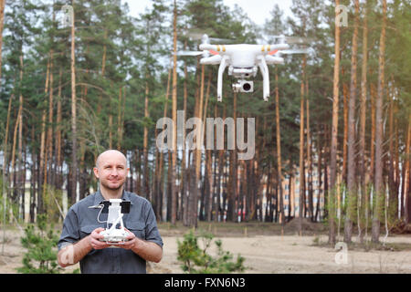 L'homme en utilisant son drone piscine avec fond de forêt Banque D'Images