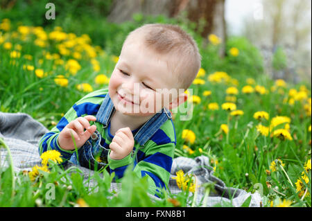 Happy little boy lying on meadow au printemps Banque D'Images