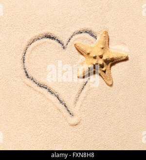 Étoile de mer sur le sable et le coeur dessiné sur le sable. Fond de plage d'été. Vue de dessus Banque D'Images