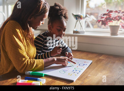 Femme et enfant alphabet d'apprentissage à la maison, mère et fille noire Banque D'Images