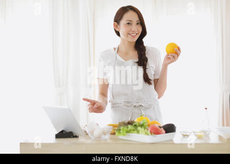 Jeune femme japonaise attrayant cooking at home with tablet Banque D'Images