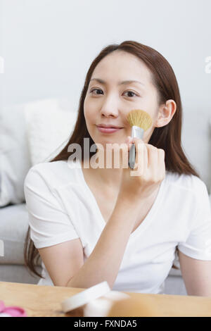 Jeune femme japonaise attrayant faisant son maquillage à la maison Banque D'Images