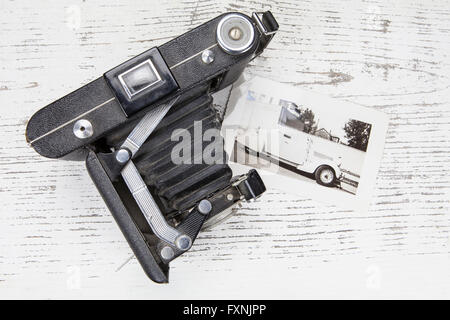 Vintage film ancien appareil photo et une vieille photo d'une voiture sur une table rustique en plongée des en noir et blanc. Banque D'Images