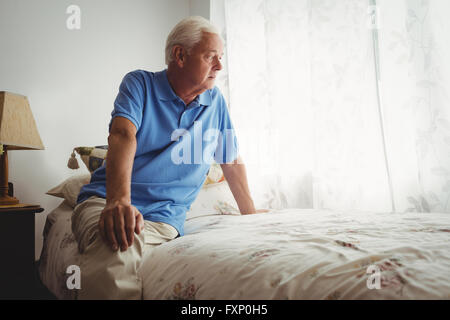 Hauts homme assis sur son lit Banque D'Images