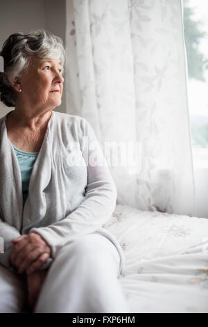 Happy woman sitting on her bed Banque D'Images