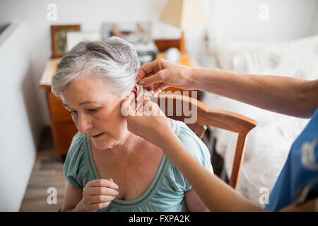 Nurse putting appareil auditif pour un senior woman Banque D'Images