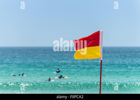 Drapeau rouge et jaune marquant la limite de la zone de baignade en toute sécurité sur une plage sous un ciel d'été bleu Banque D'Images