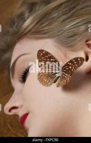 Jeune femme dormir avec un papillon sur son visage Banque D'Images