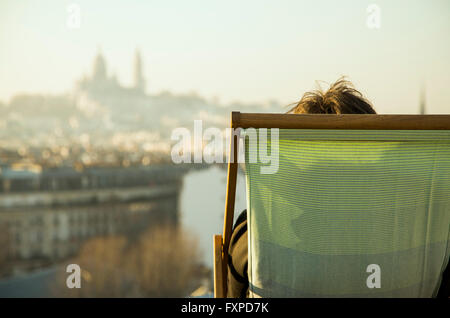 Personne assise dans une chaise longue, à la vue de la ville au Banque D'Images