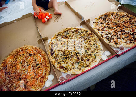 Enfant assis près de grandes pizzas en boîtes ouvertes Banque D'Images