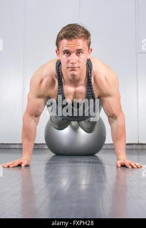 Jeune homme faisant des pompes sans avec le pilates ball Banque D'Images