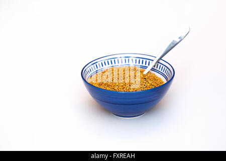 Un bol bleu de Bee pollen sur un fond blanc. Banque D'Images