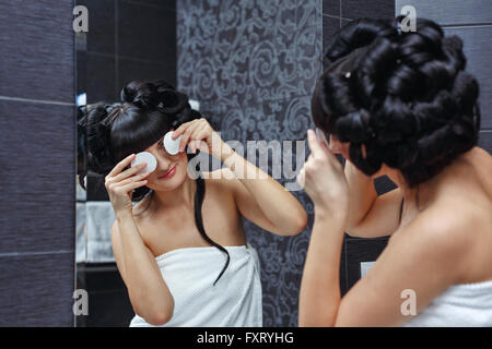 Belle fille plaisante avec un coton dans la salle de bains. Maquillage du matin. Banque D'Images