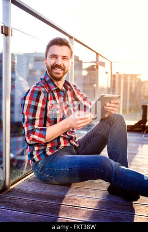 Businessman working from home sur tablet, assis sur le balcon Banque D'Images