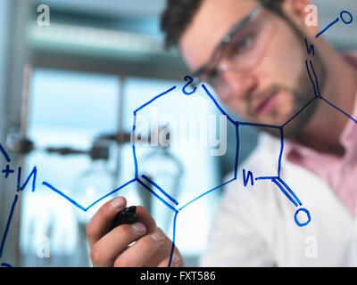 Young male scientist illustrant la formule chimique d'antibiotiques en laboratoire de recherche pharmaceutique Banque D'Images