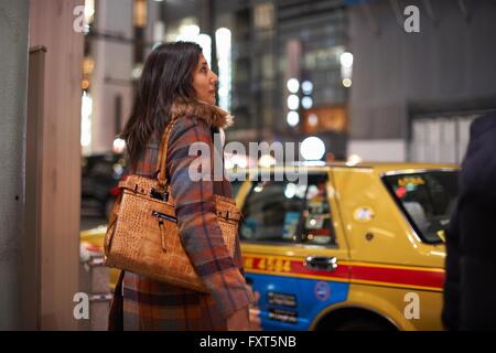 Vue latérale du sac à main de femme mature sur l'épaule en attente de cross road, Ginza, Tokyo, Japon Banque D'Images