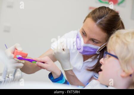 Garçon et dentiste en cabinet dentaire Le brossage des prothèses dentaires Banque D'Images