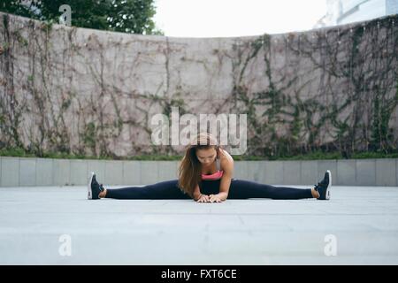 Jeune femme faisant de l'exercice en plein air les scissions Banque D'Images