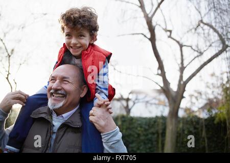 Homme mûr exerçant son petit-fils sur les épaules en souriant Banque D'Images