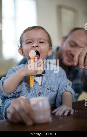 Se nourrir bébé garçon yaourt avec spoon, bouche ouverte Banque D'Images