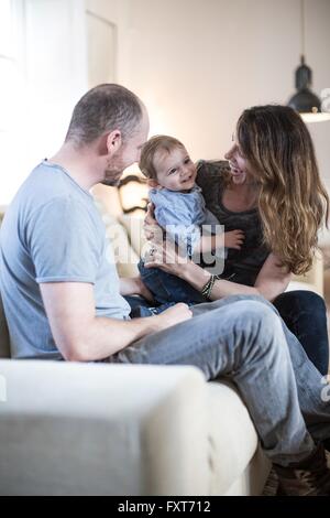 Les parents assis sur un canapé à jouer avec smiling baby boy Banque D'Images