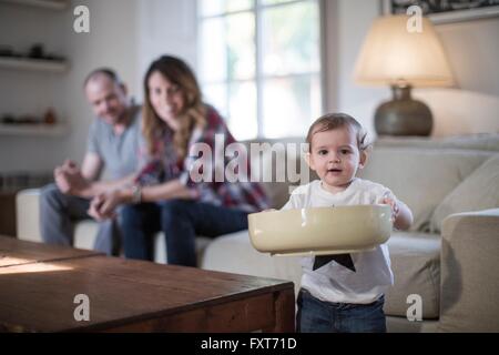 Baby Boy in living room holding grand bol looking at camera smiling Banque D'Images