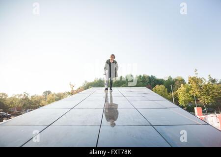 Portrait of young male skateboarder urbain debout sur le toit de Banque D'Images