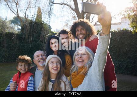 Multi generation family entassés en utilisant smartphone pour prendre, souriant selfies Banque D'Images