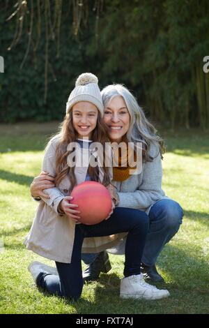 Grand-mère et petite-fille holding football looking at camera smiling Banque D'Images