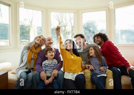 Multi generation family sur la fenêtre siège à l'aide de prendre smartphone selfies Banque D'Images